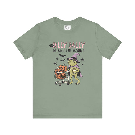 Green t-shirt with Halloween-themed graphic and text on a white background 
dilly dally  frog and pumpkin